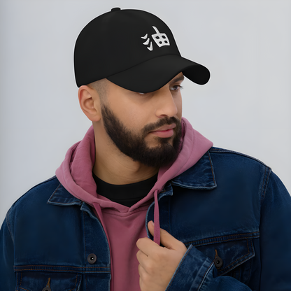 A model wearing a black cap with kanji characters, shown from the side to highlight the cap’s design and the bold, cultural statement made by the kanji in the overall look.