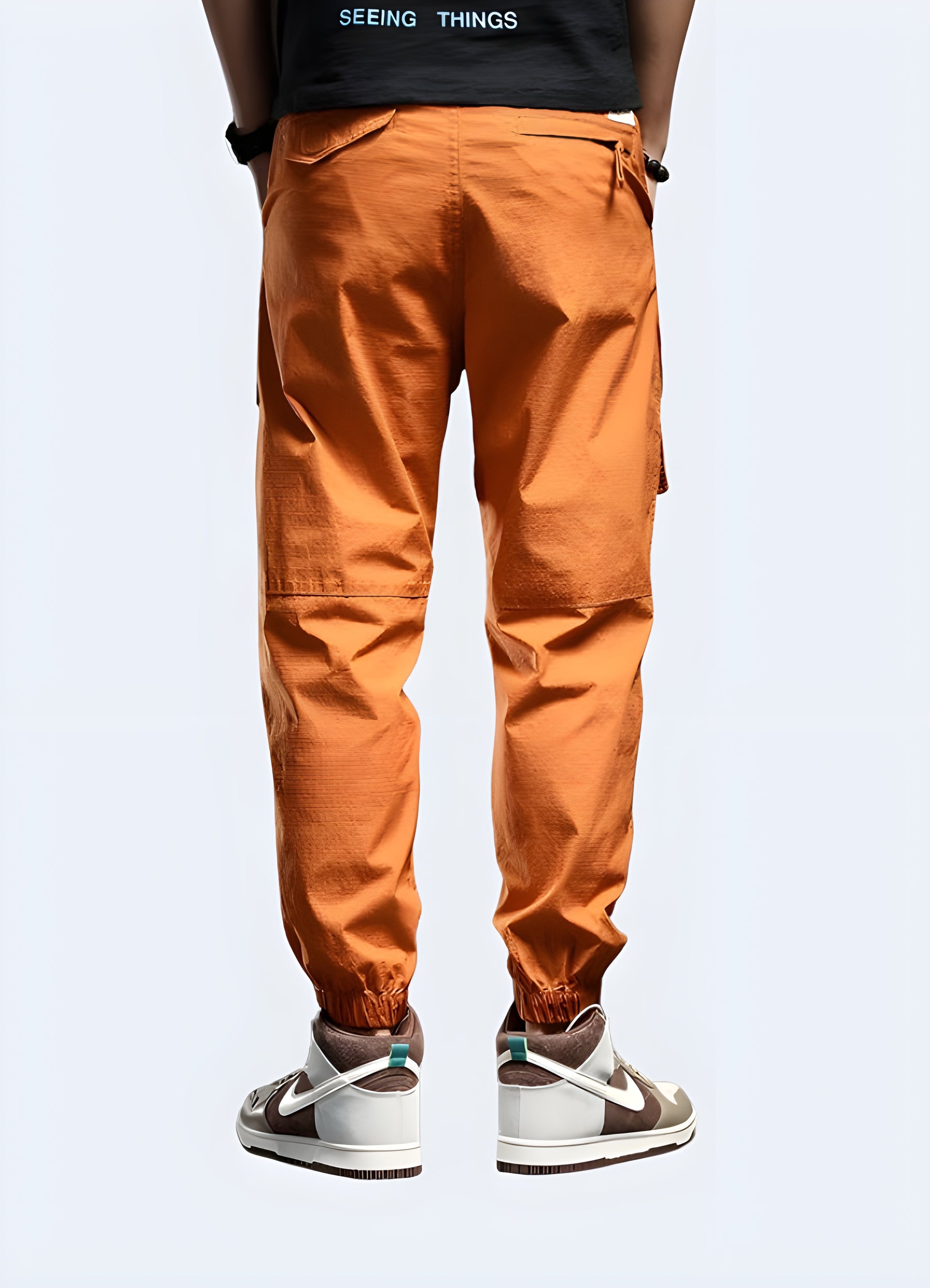 Futuristic orange techwear pants men wearing back view.
