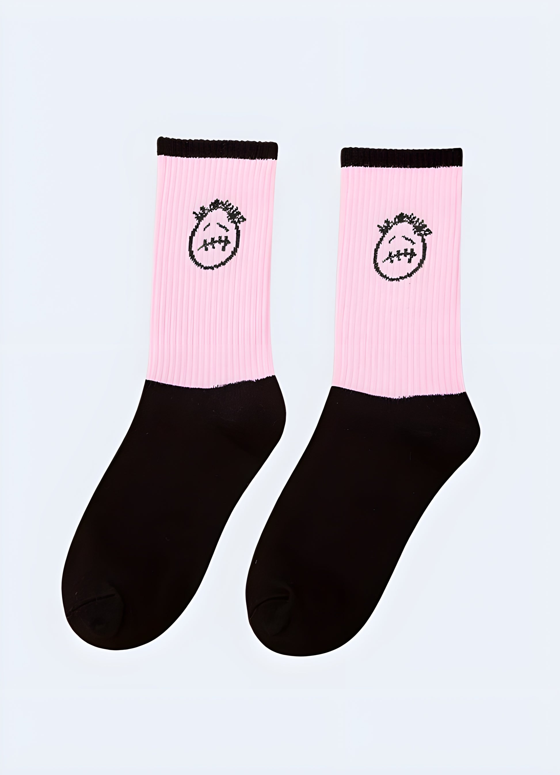 A pair of black crew socks with a large, expressive sad face embroidered on the front in white thread.