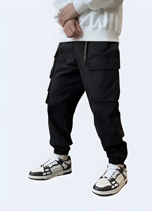 The pants have a slim, tapered fit with multiple utilitarian pockets, including large thigh pockets with zippers and smaller compartments.