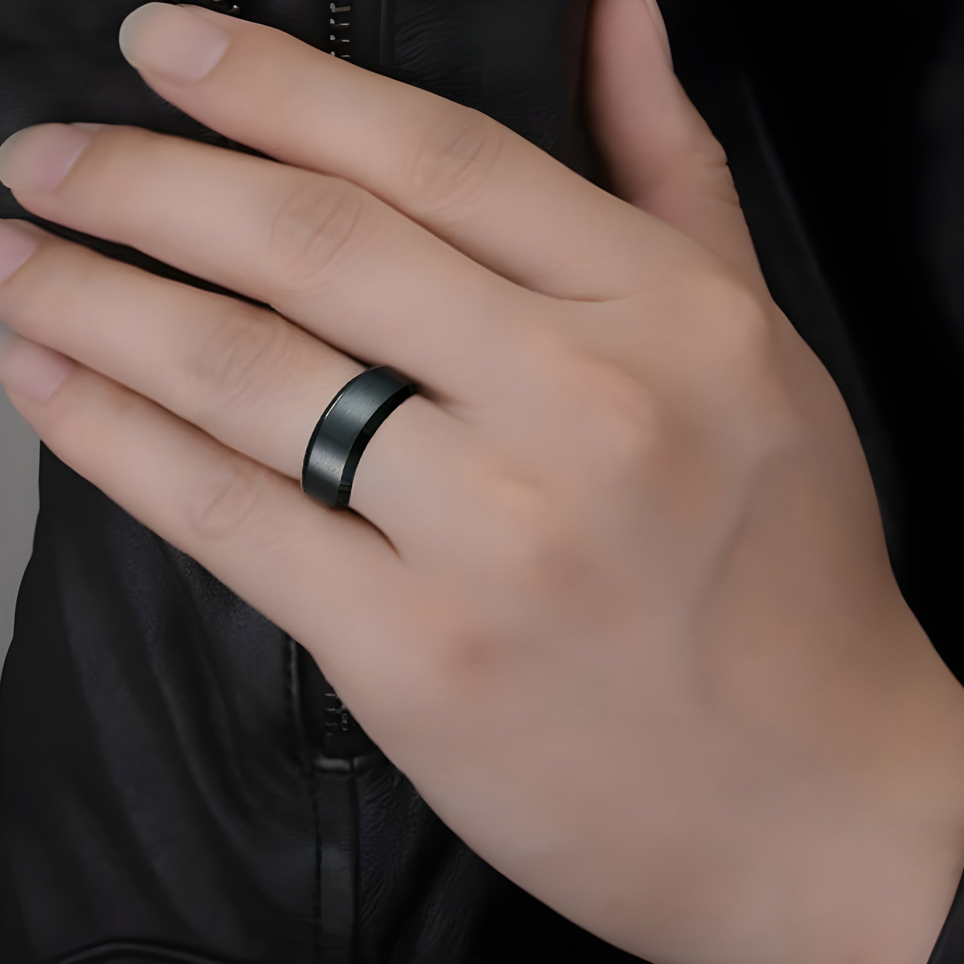 Person wearing a black titanium ring, shown in a front view, highlighting the sleek and modern design of the ring.